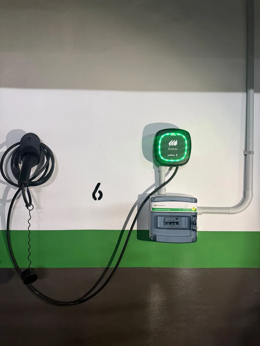 Punto de recarga mural con cable y cuadro de protecciones en un garaje